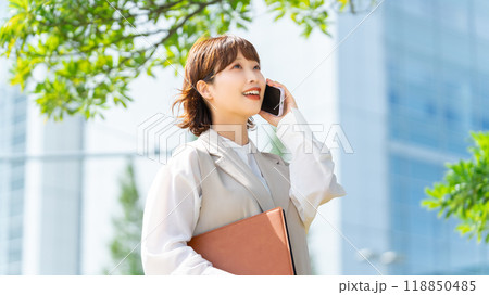 オフィス街でスマホで話すビジネスウーマン オフィス街でスマホで話すビジネスウーマン 118850485