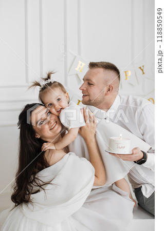 Joyful family celebrating child's birthday with cake indoors 118850549