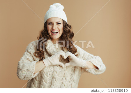 smiling woman showing heart hands against beige 118850910