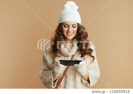 happy woman against beige sending text message using phone happy woman against beige sending text message using phone 118850918