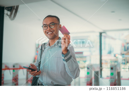 A joyful young man is happily holding a card in a vibrant modern urban setting 118851186