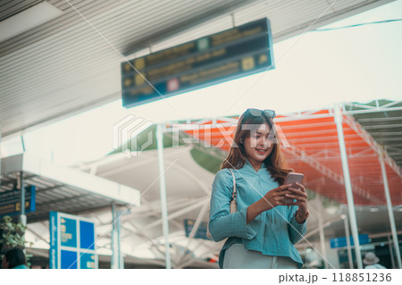 A Happy Traveler is seen at the Airport Checking Their Mobile Phone in Excitement A Happy Traveler is seen at the Airport Checking Their Mobile Phone in Excitement 118851236