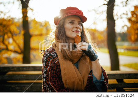 pensive trendy woman in red hat with autumn leaf 118851524