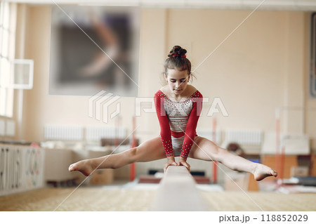 Child gymnastics balance beam. Girl gymnast athlete during an exercise horizontal bar in gymnastics competitions. Child gymnastics balance beam. Girl gymnast athlete during an exercise horizontal bar in gymnastics competitions. 118852029