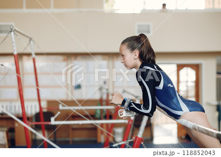 Child gymnastics balance beam. Girl gymnast athlete during an exercise horizontal bar in gymnastics competitions. Child gymnastics balance beam. Girl gymnast athlete during an exercise horizontal bar in gymnastics competitions. 118852043