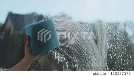 Woman in rubber gloves sprays window cleaner from a spray bottle onto the windows glass. Housewife hands in rubber gloves cleaning windows close up. Cleaning glass window with a cloth special rag blue Woman in rubber gloves sprays window cleaner from a spray bottle onto the windows glass. Housewife hands in rubber gloves cleaning windows close up. Cleaning glass window with a cloth special rag blue 118852576