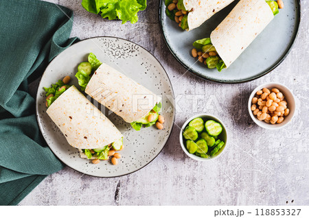 Tortilla wraps with cucumber, white beans and lettuce on a plate on a table top view 118853327