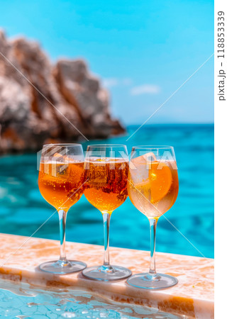Three glasses with rose wine and Aperol Spritz cocktail, cafe menu advertising concept, vertical poster on blue sea background Three glasses with rose wine and Aperol Spritz cocktail, cafe menu advertising concept, vertical poster on blue sea background 118853339