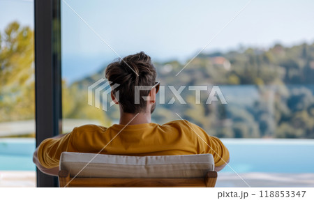 Rear view of young man in sun lounger on swimming pool background, vacation advertising concept 118853347