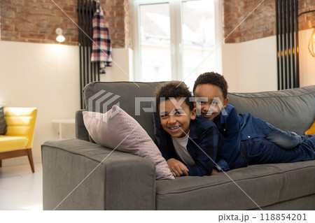 Cheerful kids lying together on sofa and having fun at home Cheerful kids lying together on sofa and having fun at home 118854201