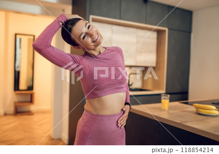 Young woman dressed in pink sportswear performing yoga stretches to improve strength 118854214