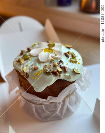 Beautifully decorated cake on a table, adorned with green icing and sprinkled with nuts and meringue pieces. Pastry is wrapped elegantly, perfect treat for special holidays. Sweet food and delicious Beautifully decorated cake on a table, adorned with green icing and sprinkled with nuts and meringue pieces. Pastry is wrapped elegantly, perfect treat for special holidays. Sweet food and delicious 118854309