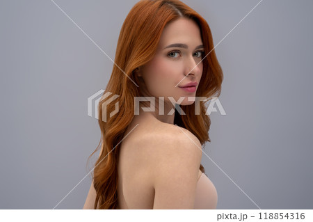 Cute young woman with long ginger hair on a grey background Cute young woman with long ginger hair on a grey background 118854316