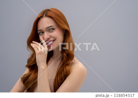 Cute young woman with long ginger hair on a grey background Cute young woman with long ginger hair on a grey background 118854317