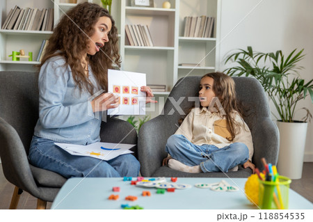 Long-haired cute girl working with a speech therapist and looking attentive 118854535