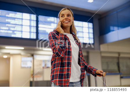 A Cheerful and Joyful Traveler at the Airport, Happily Engaged in a Phone Conversation 118855493