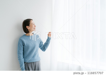 カーテンを開けて外を見る女性 118857707