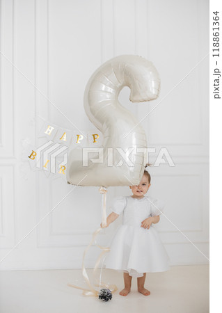 Joyful toddler celebrating second birthday with large balloon Joyful toddler celebrating second birthday with large balloon 118861364