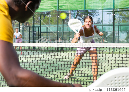 Young woman playing padel tennis on court against man Young woman playing padel tennis on court against man 118861665