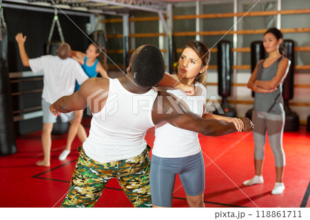Girl self defense training gym learning to do painful grip 118861711