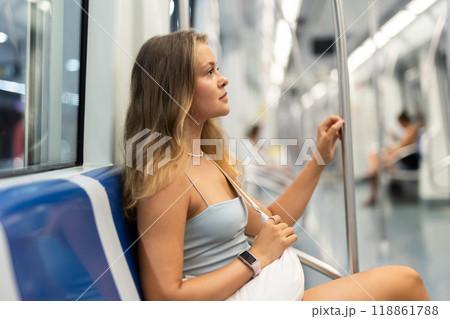 During trip to work in subway car, girl passenger sits on seat 118861788