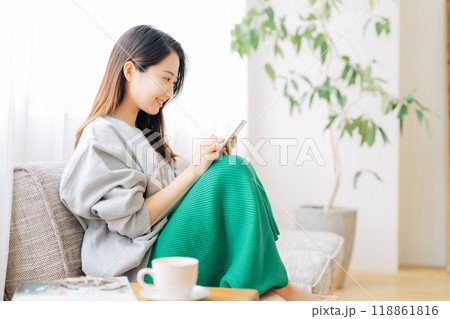 ソファに座ってスマホを見る女性 118861816