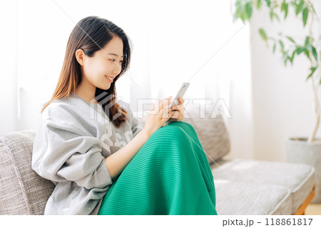 ソファに座ってスマホを見る女性 118861817