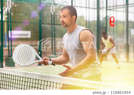 Young adult men playing doubles paddle tennis Young adult men playing doubles paddle tennis 118861954