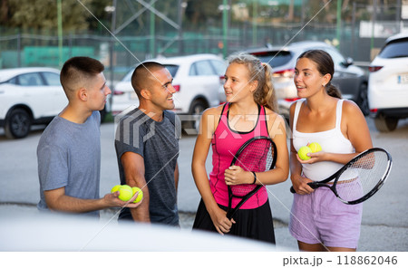 Group portrait of team of tennis players standing at parking near courts and discussing tennis match Group portrait of team of tennis players standing at parking near courts and discussing tennis match 118862046