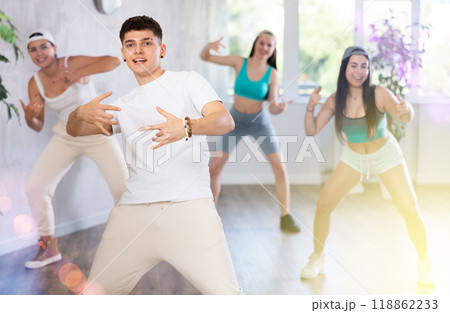 Positive male teenager learns to dance, perform movements in choreographic class in company of peers Positive male teenager learns to dance, perform movements in choreographic class in company of peers 118862233