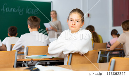 Teen girl listening to lecturer and writing in notebook Teen girl listening to lecturer and writing in notebook 118862235