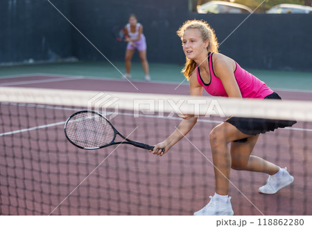 Girl playing tennis ball friendly match on outdoors court Girl playing tennis ball friendly match on outdoors court 118862280