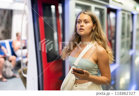 Girl with phone is standing on subway platform, waiting for train to arrive 118862327