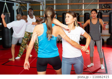 Men and women exercising self-protection moves in gym Men and women exercising self-protection moves in gym 118862415