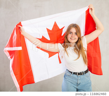 Joyful female fan of the favorite team of Canada with the national flag in hands Joyful female fan of the favorite team of Canada with the national flag in hands 118862460