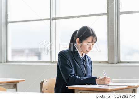 学校の教室で英語の教科書・参考書を見ながら勉強する女子高校生・中学生の生徒 学校の教室で英語の教科書・参考書を見ながら勉強する女子高校生・中学生の生徒 118862774