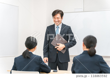 塾・学校の教室で中学生・高校生に勉強を教える男性講師・教師 118863592