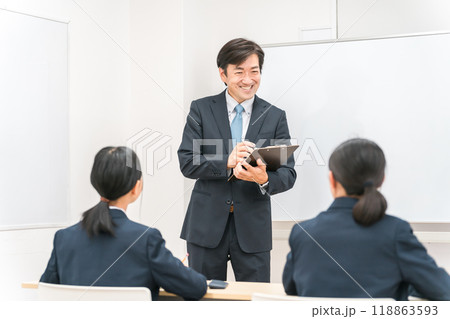 笑顔で教えるアジア人男性塾講師・教師・先生と話を聞く学生・生徒 笑顔で教えるアジア人男性塾講師・教師・先生と話を聞く学生・生徒 118863593