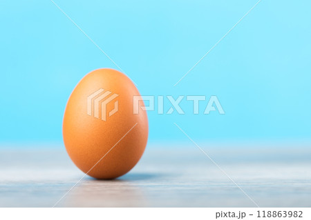 Single fresh egg rests on a table against a light blue, symbolizing nature nutrition and wholesome food choices. Emphasizes the simplicity and purity of basic ingredients in a balanced diet 118863982