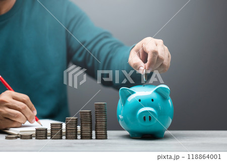 Man is dropping coins into a blue piggy bank, symbolizing the act of saving and financial responsibility. Financial planning, budgeting, and building a stable future through consistent savings 118864001