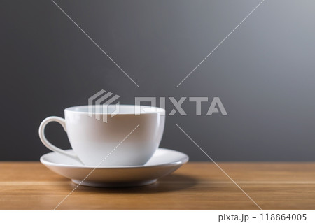 White coffee cup sits on a wooden table against a dark gray background. The image conveys warmth, simplicity, and the comfort of enjoying a fresh cup of coffee 118864005