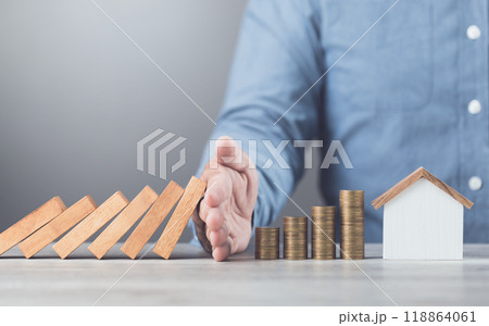 Businessman uses his hand to stop wooden blocks from falling, symbolizing the protection of assets and strategic decision-making in managing resources effectively, domino effect and risk management Businessman uses his hand to stop wooden blocks from falling, symbolizing the protection of assets and strategic decision-making in managing resources effectively, domino effect and risk management 118864061