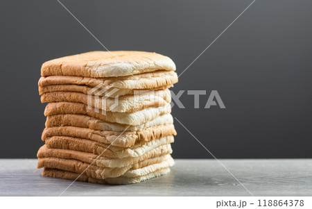 Slices of bread stacked on a gray wooden table against a dark gray background. The image symbolizes the connection between food, nutrition, and maintaining good health. 118864378