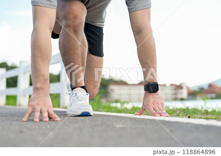 A cropped image of an active man in sportswear in a ready-to-run position, preparing to sprint. A cropped image of an active man in sportswear in a ready-to-run position, preparing to sprint. 118864896