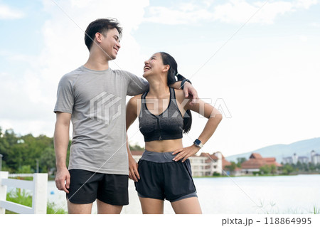 A lovely, sporty Asian couple smiles and gazes into each other's eyes, enjoying a run together. 118864995