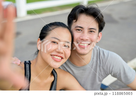 A lovely, sporty Asian couple in sportswear is taking a selfie together after their morning run. 118865003