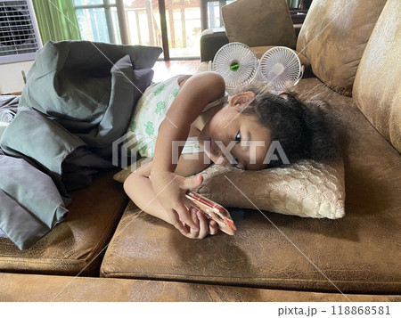 Little Asian girl using smartphone on sofa at home. Little Asian girl using smartphone on sofa at home. 118868581