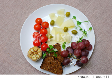 cut cheese into slices on a plate with cherry tomatoes grapes and olives microgreens decoration serving cheese in a restaurant 118869511