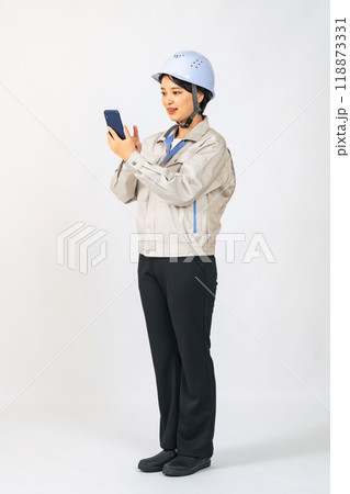 スマホを使うヘルメットと作業服を着た女性　作業員　エンジニア　切り抜き全身写真 118873331