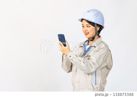 スマホを使うヘルメットと作業服を着た女性　作業員　エンジニア 118873388